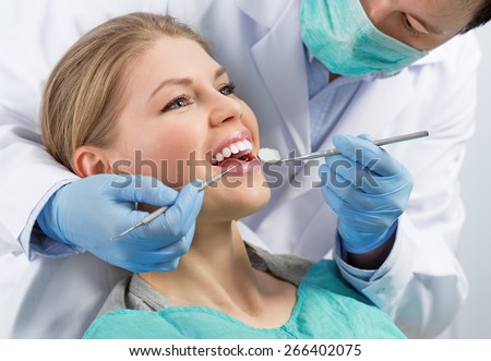 Gingivitis therapy. Male surgeon examining female's molar before treatment in dental clinic.
