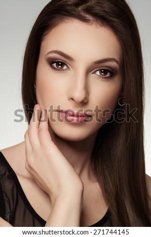 Portrait of long straight hair model with professional makeup. Young Caucasian lovely woman touching her clean healthy skin.
