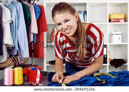 Clothing repair service. Pretty woman measuring textile with tape in workroom. Concept of small business.