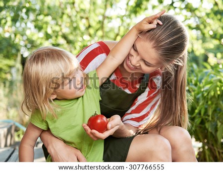 Portrait of happy mother and her little daughter playing in the kitchen garden. Family gardening activity.