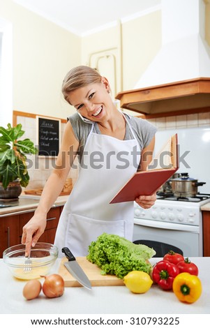 Young business woman working on phone and preparing meal with recipe book. Concept of diet and healthy nutrition.