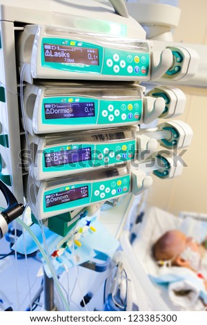 syringe pumps in pediatric intensive care unit with child on background