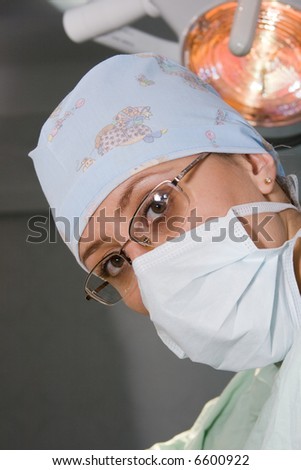 young surgeon woman with mask under lamp