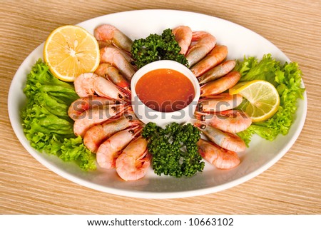 shrimps with lemon, sauce and lettuce on table