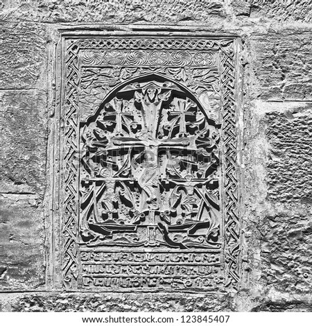 A cross carved in stone on the wall in Jerusalem - Israel (black and white)