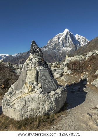 Carved stone tablets, each with the inscription Om Mani Padme Hum on the background of Tabuche peak - Everest region, Nepal, Himalayas