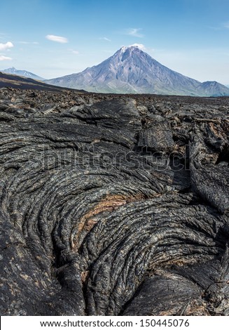 The active lava flow from a new crater on the slopes of volcanoes Tolbachic, on background volcano Bolshaya Udina - Kamchatka, Russia
