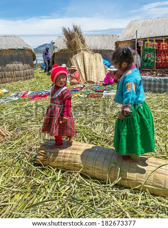 TITICACA, PERU - JAN 03, 2014: Unidentified indian children welcome tourists on island Uros in Lake Titicaca. The Qhichwa Uros are a pre-Incan people who live on 42 self-fashioned floating islands