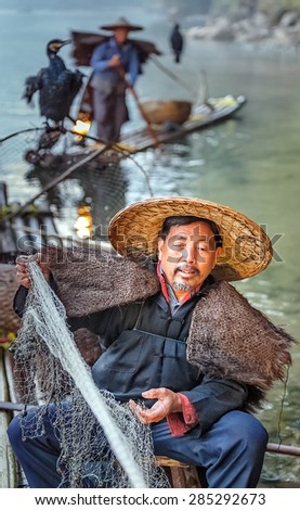 XINGPING, CHINA - OCTOBER 22, 2014: Cormorant fishermen on ancient bamboo boats with lighted lamps and cormorants - The Li River, Xingping, China