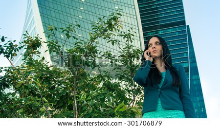 Business woman speaks on the phone on the background of skyscrapers of glass.