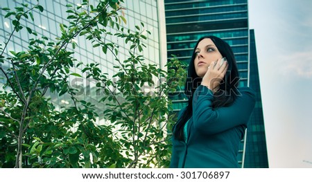 Business woman speaks on the phone on the background of skyscrapers of glass.
