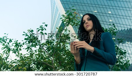 Impressive business woman holding the phone in front of the building business.