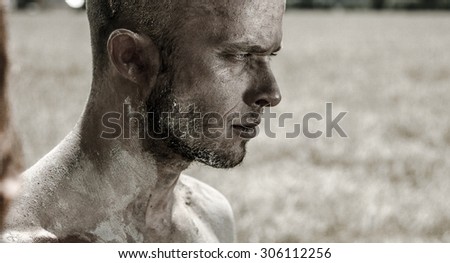 A bald man walking in the field in the mud, sand and clay without clothes.