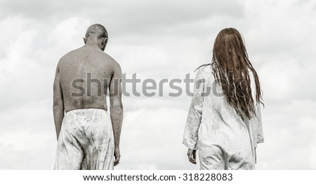 Man and woman walk hand in hand on background of sky and clouds. The man in white trousers, the woman in the white plane.