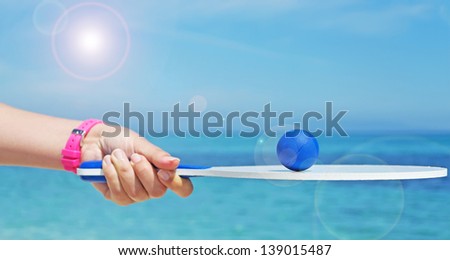 girl holding a white beach racket with a blue ball on it