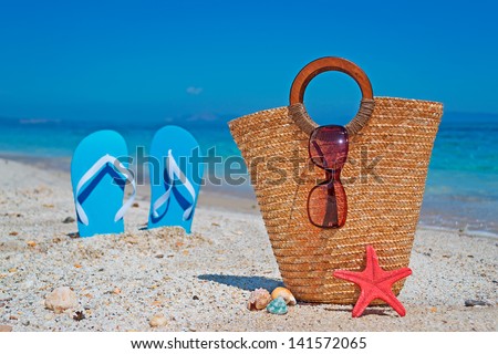 straw bag by the shore with blue sandals on the background