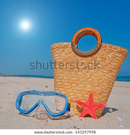 straw bag, diving mask and starfish on the beach