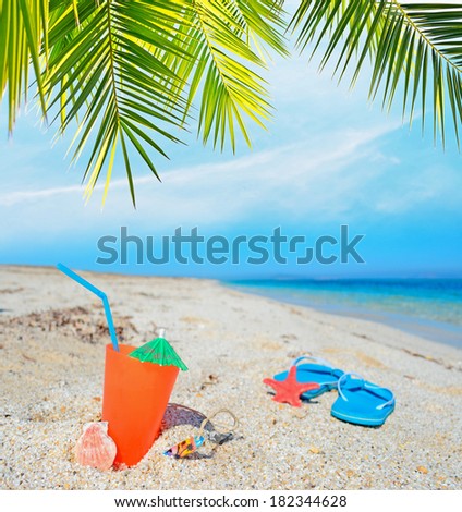 orange drink and blue sandals under a palm branch
