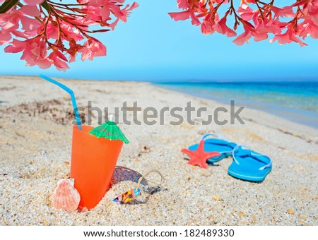 orange drink and blue sandals under red flowers