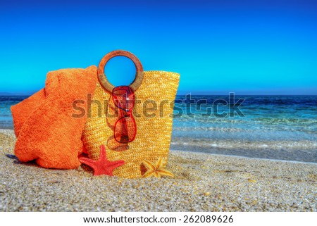 straw bag, beach towel and sunglasses on the sand in hdr