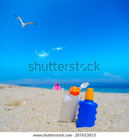 seagull flying over the suntan lotion bottles on a white sand