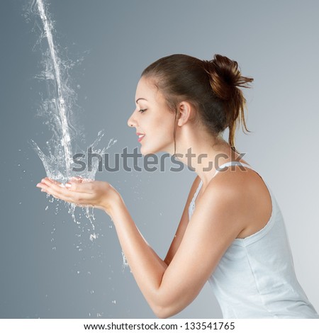 Young woman washing her face and hands with clean water in the morning - stock photo