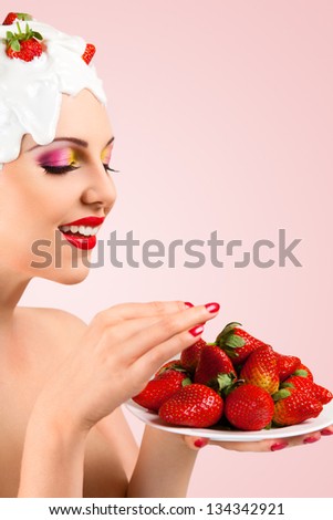 Young woman with hairstyle made from milk eating red ripe strawberry