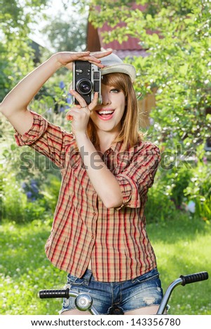 Young woman making photos with vintage film camera at summer green park.