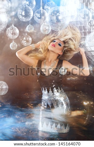 Young blonde woman dancing at night disco club. Motion blur