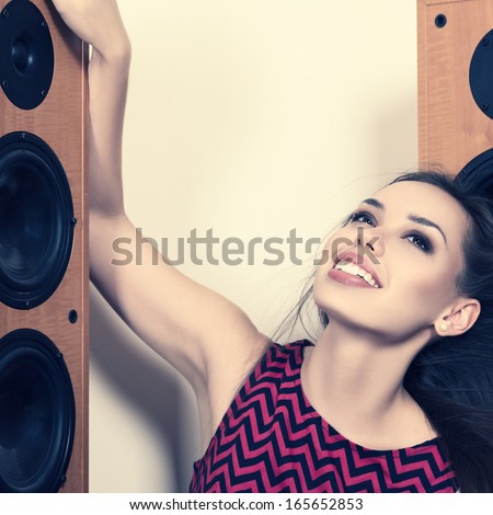 Young woman listening music in front of big speakers