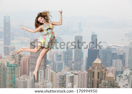 Young fashion model high jumping against cityscape view