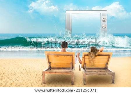 Young couple relaxing lying down on a beach chair and watch tv