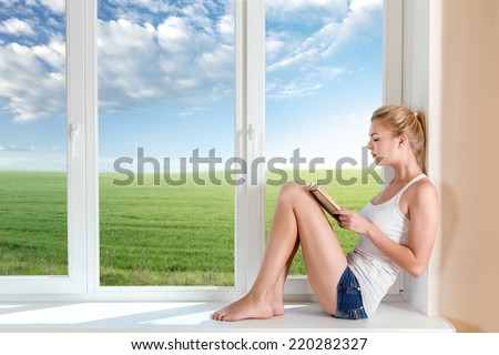 Young woman read book sitting on windowsill
