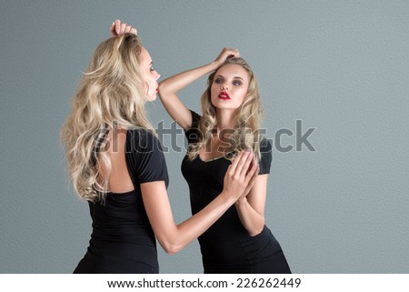 Young beautiful blonde woman in black mini dress combined with mirror reflection