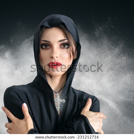 Young sad beautiful woman in black hood with cross