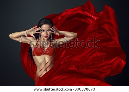 Beautiful belly dancer perfoming exotic dance in red flutter dress