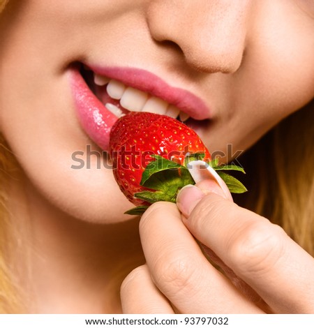 Young woman eating mellow strawberry closeup