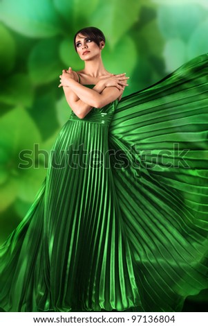 Sexy young girl in long flowing dress against green nature background