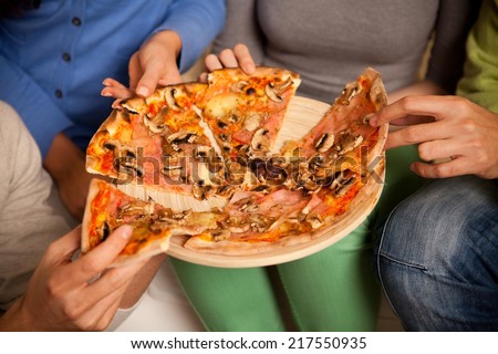 Close up of a four friends sharing pizza.