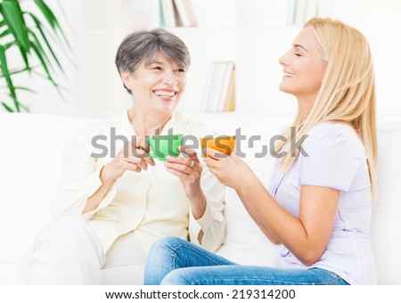 Mother and daughter sharing a cup of coffee in their living room.