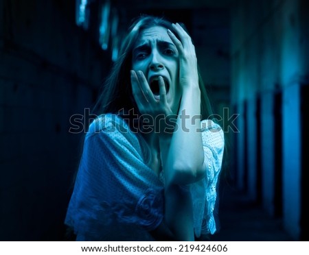 Scary woman screaming in a dark hallway.