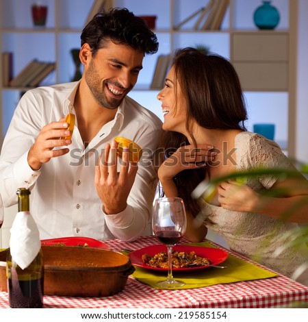 Romantic couple having dinner at home. Man giving present to a woman.