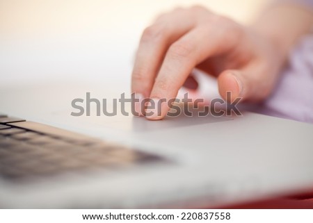 Close up of a female hand touching touch pad of a laptop.