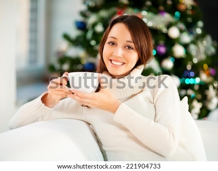 Young beautiful woman sitting on the sofa and drinking tea or coffee.