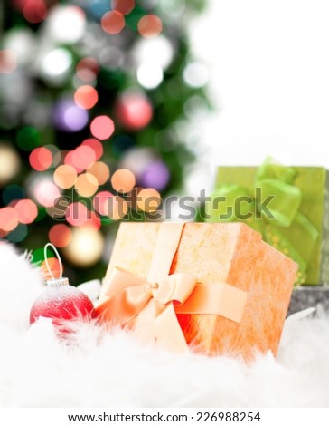 Close up of a Christmas tree decoration and gift box - woman decorating christmas tree in the background