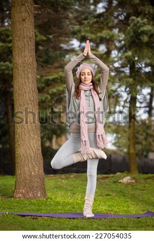 Young woman practising yoga in the park - tree pose.