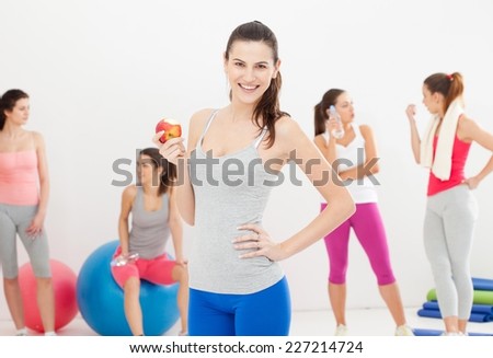 Young women doing aerobics in a studio. Having a break and eating apple. Focus on foreground.