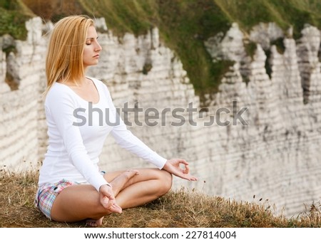 Young woman practising yoga on the cliff - meditation, close up.