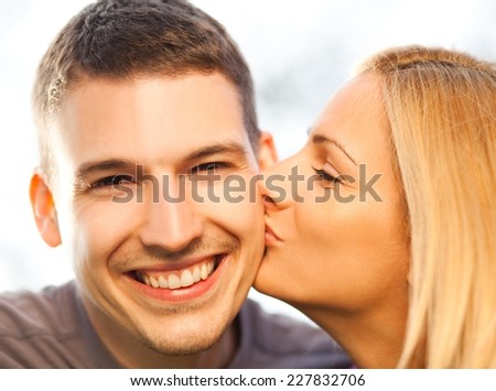 Young couple - woman kissing man on the cheek