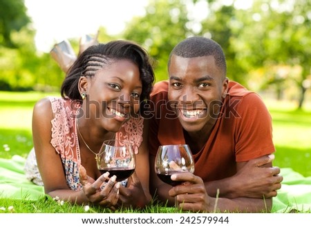 Young black couple enjoying sunny day and drinking wine in the park.